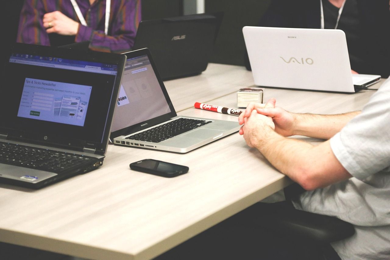 People working side by side on laptops at a shared table