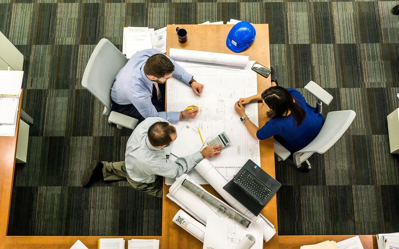 Overhead view of a team planning around a table of drawings and notes
